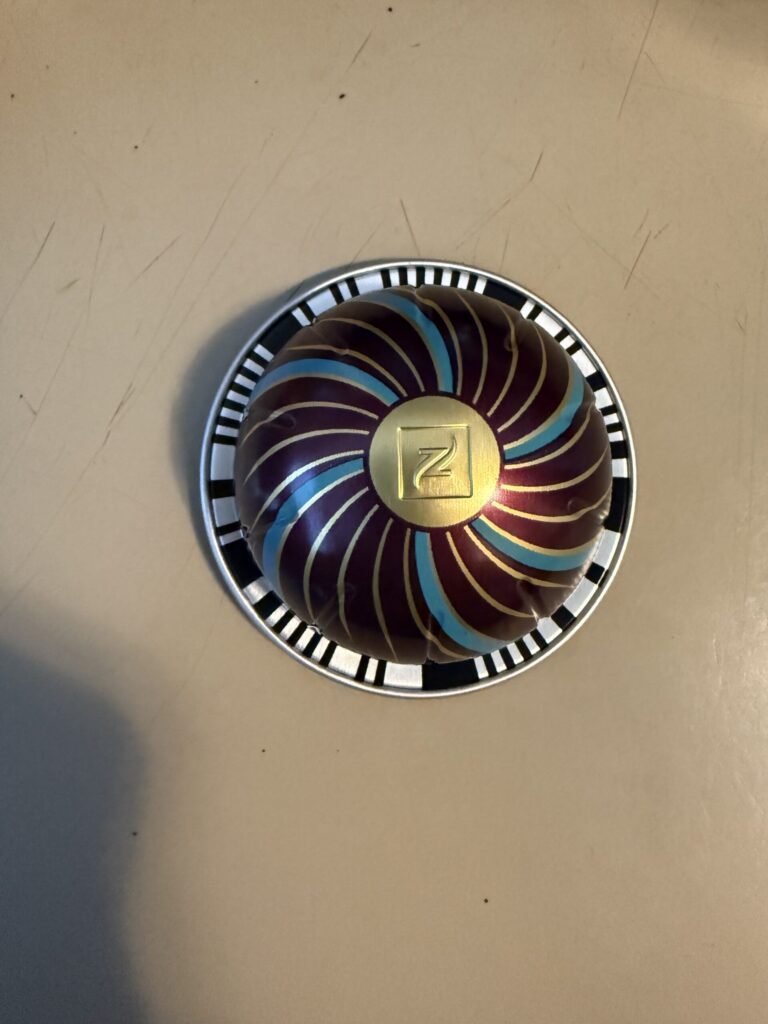 a nespresso pod with gold blue and a plummy brown